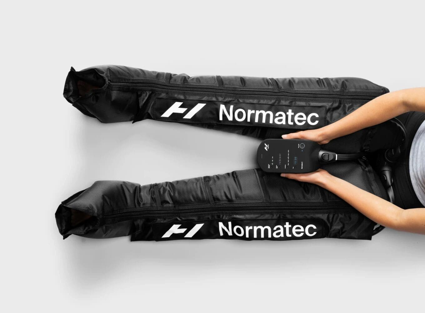 Person using Normatec leg compression therapy device.