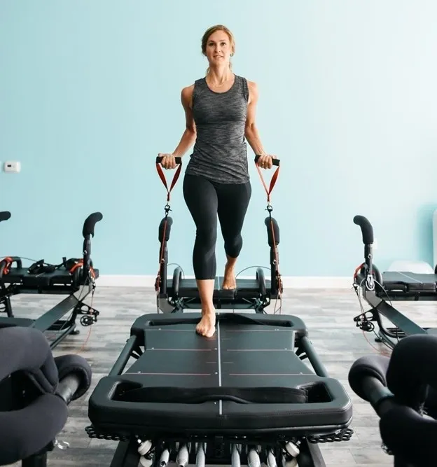 Woman exercising on a Pilates reformer machine.