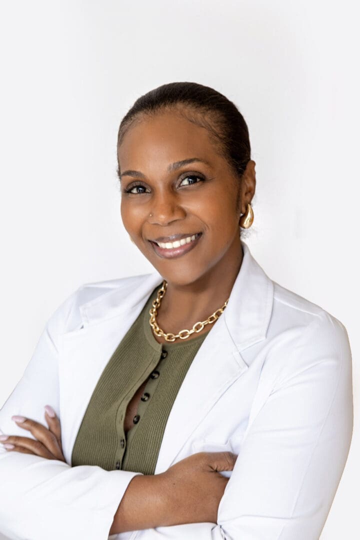 Smiling woman in white coat, arms crossed.
